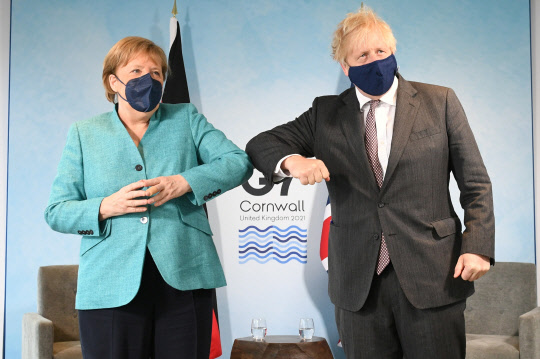 Britain's Prime Minister Boris Johnson and German Chancellor Angela Merkel elbow bump as they attend a bilateral meeting during G7 summit in Carbis Bay, Cornwall, Britain, June 12, 2021. Stefan Rousseau/Pool via REUTERS